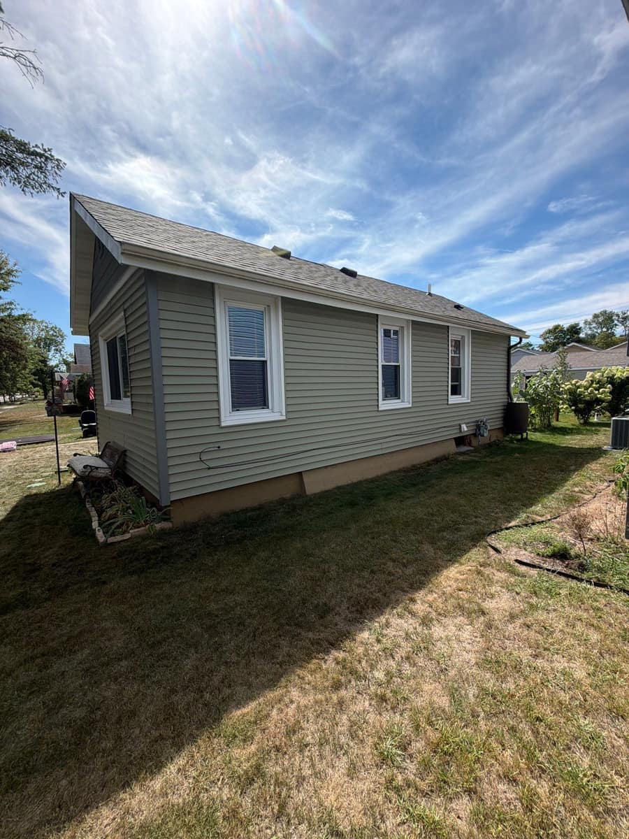 Side of a sage-green single-story St. Cloud home with a new shingle roof and gutters