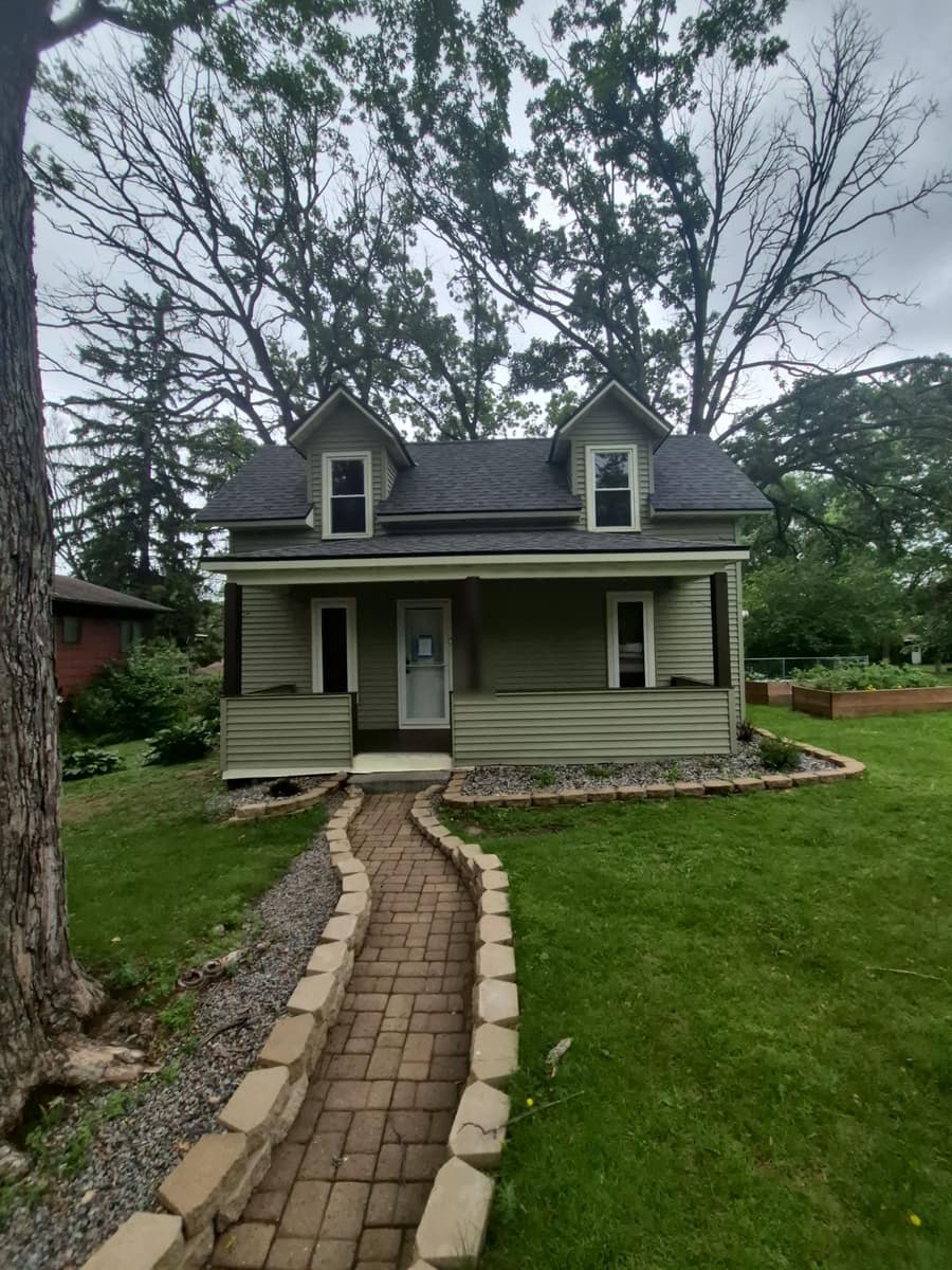 Front of a green-sided story-and-a-half St. Cloud, MN home with a new dark shingle roof and dormers
