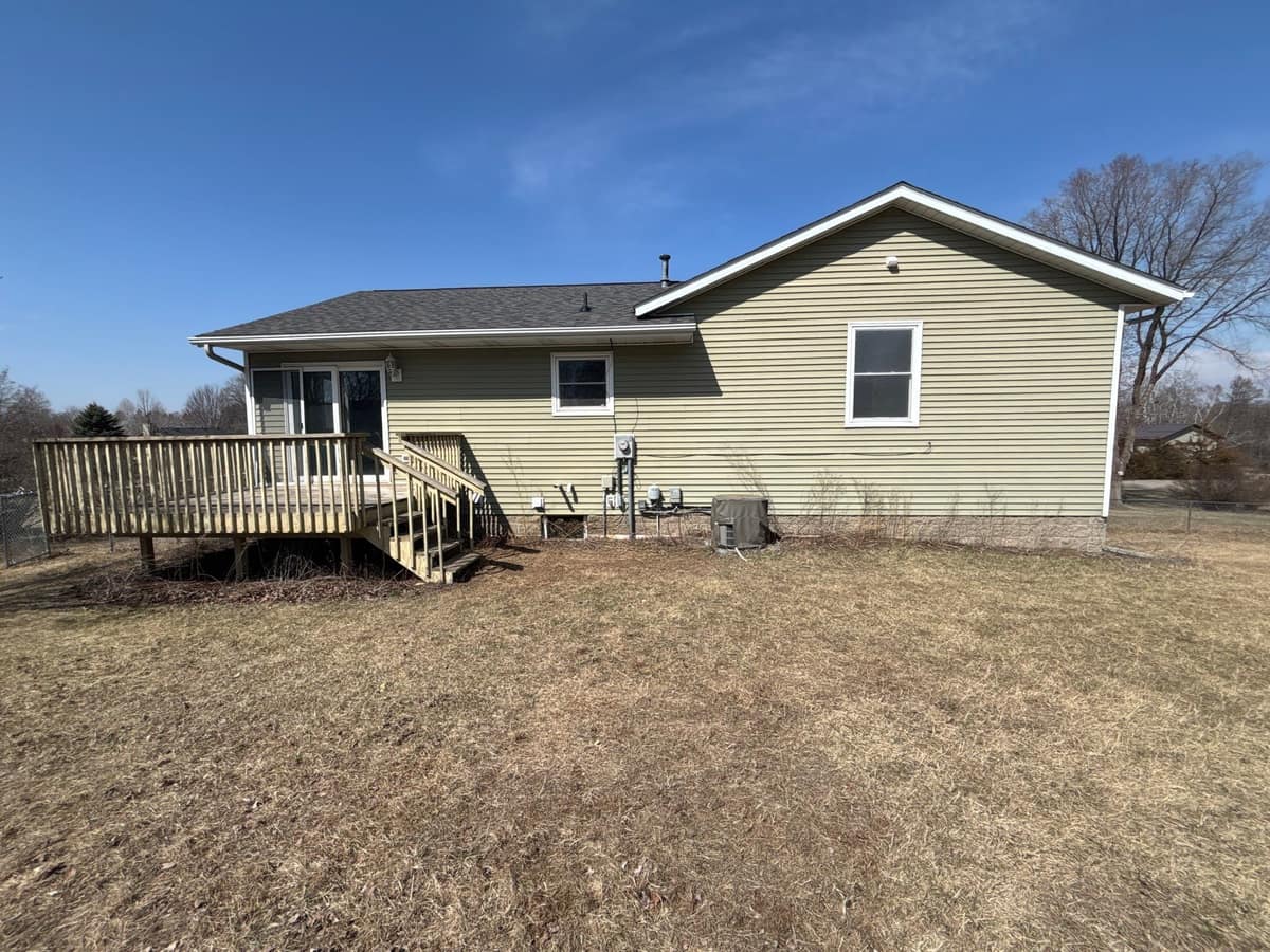 Back of a St. Joseph home with new sage green vinyl siding, a gray shingle roof and a wood deck