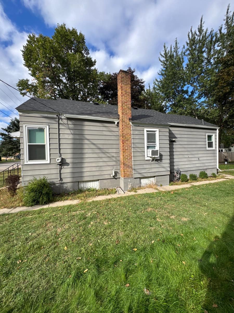 Small gray-sided Waite Park, MN home with a brick chimney and a new dark shingle roof