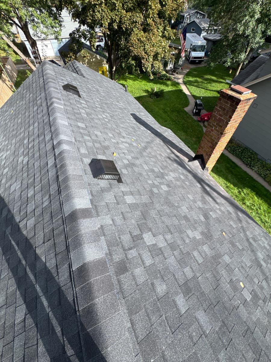 New charcoal shingles and roof vent beside the chimney in Waite Park